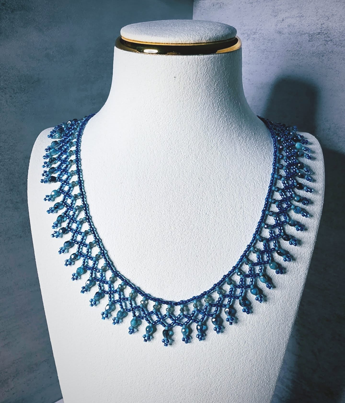 Hand-woven collar necklace in cobalt and turquoise glass beads, displayed on a white bust